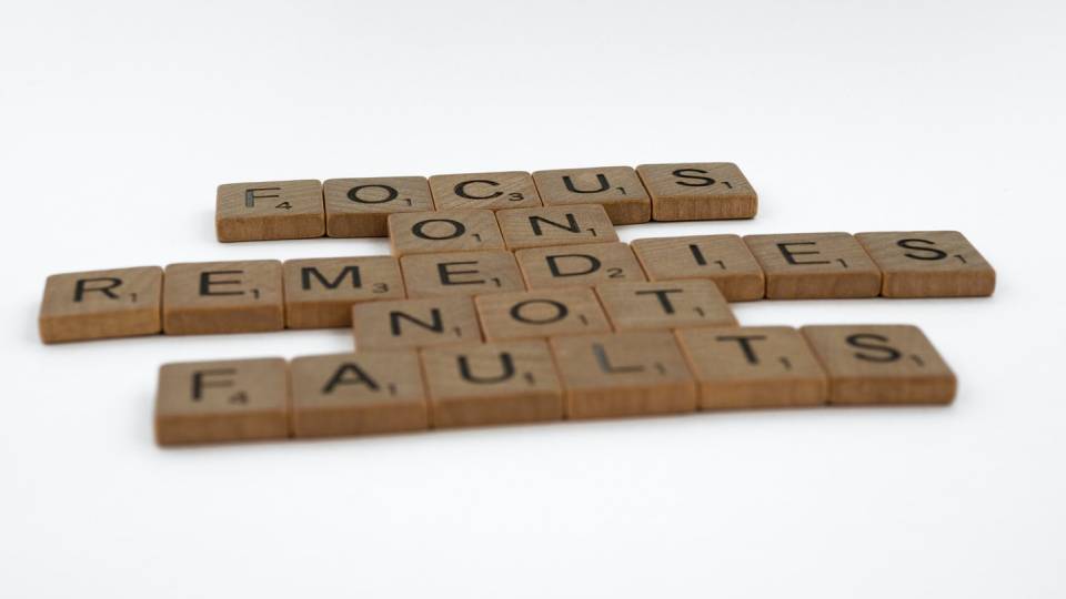 A picture of wooden scrabble showing the words focus on remediation not faults depicting