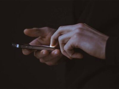 A picture of a man holding his phone. this image is attached to a blog article titled: Vulnerability Management, make the most of your ongoing efforts with 1 KPI through the Hackability Score that prioritizes issues for IT teams and why benefits fourfold from just 1 single KPI.