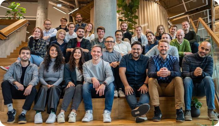 A group picture of Autobahn Security's team in a bright office setting, smiling and sitting on tiered wooden stairs.