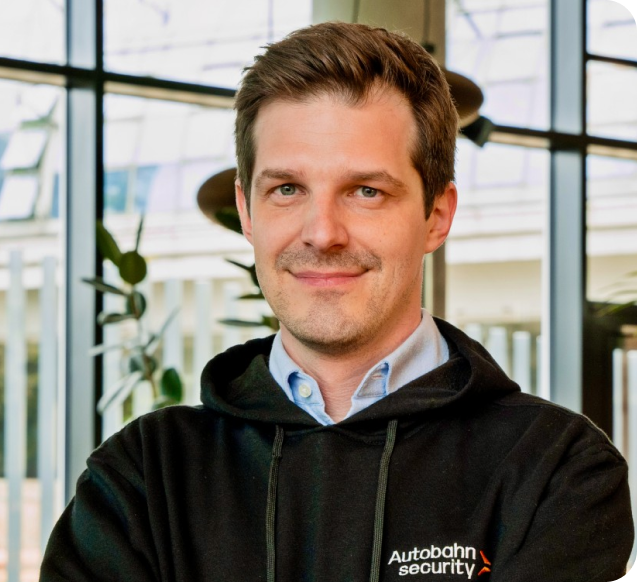 Portrait photo of Autobahn Security CEO Aleksander Groshev wearing a black branded hoodie of the company at an office.